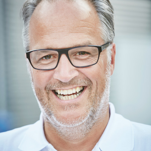 Bildbeschreibung: Im Profilbild ist Marco Kleemeyer. Er lächelt in die Kamera und hat dunkelgraue Haare sowie einen Bart. Er trägt eine schwarze Hornbrille und ein weißes Hemd.
